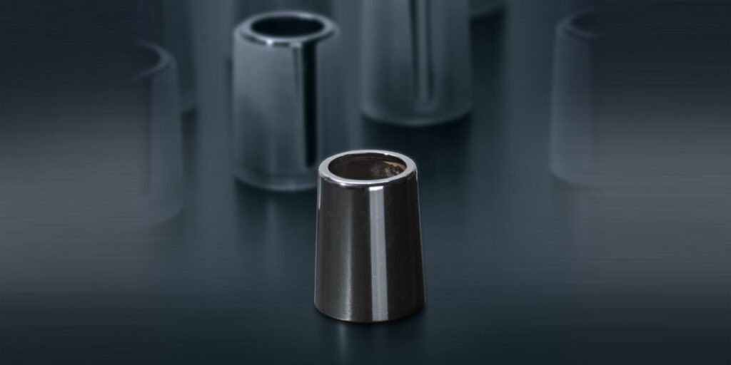 Konische Metallhülse mit spiegelnder Oberfläche, gleichartige Teile unscharf im Hintergrund